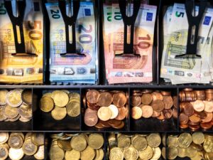 Kasse mit Geldscheinen und Münzen in Euro